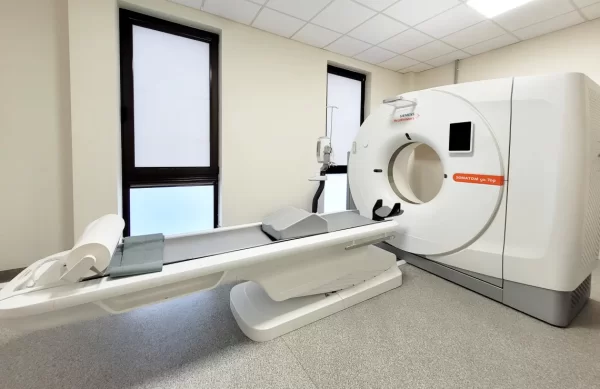 Kompiuterinės tomografijos (KT) aparatas klinikos kabinete su paciento gultu