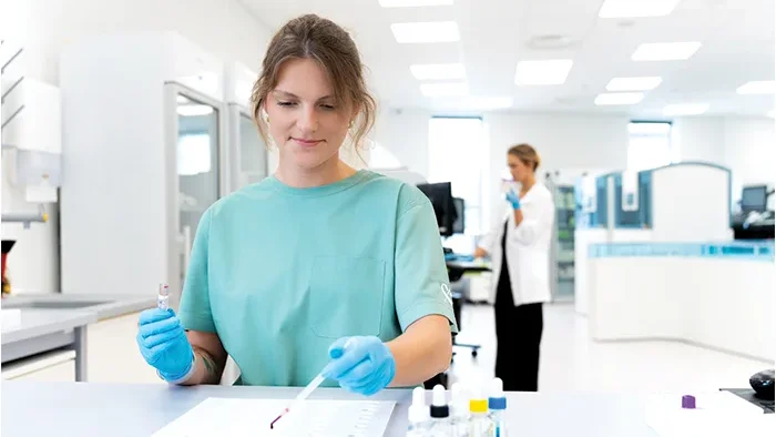 Mėlyna apranga apsirengusi mergina dirba laboratorijoje 
