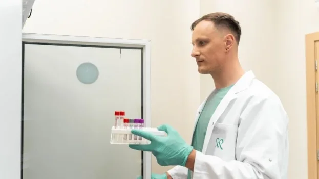 Vyras su baltu chalatu rankose laiko laboratorinius mėgintuvėlius