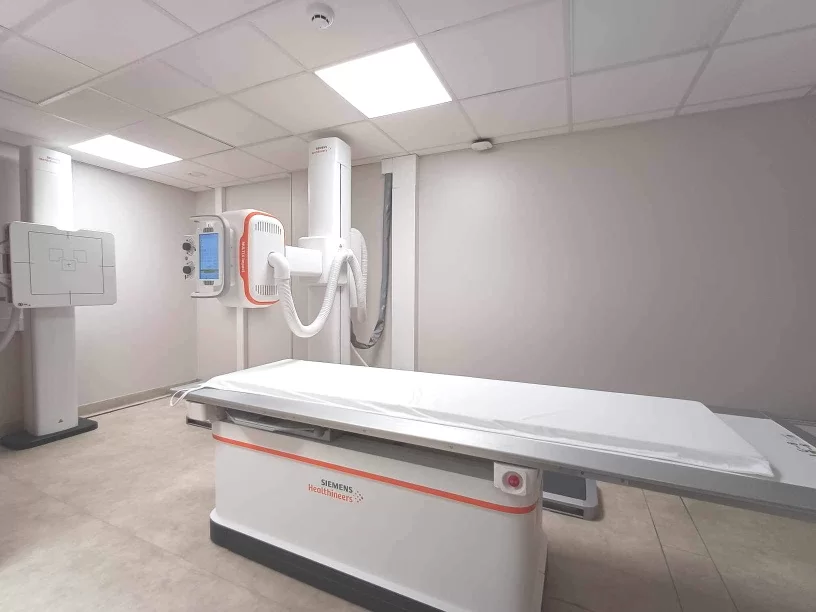 Skaitmeninis rentgeno aparatas klinikos kabinete su tyrimų stalu