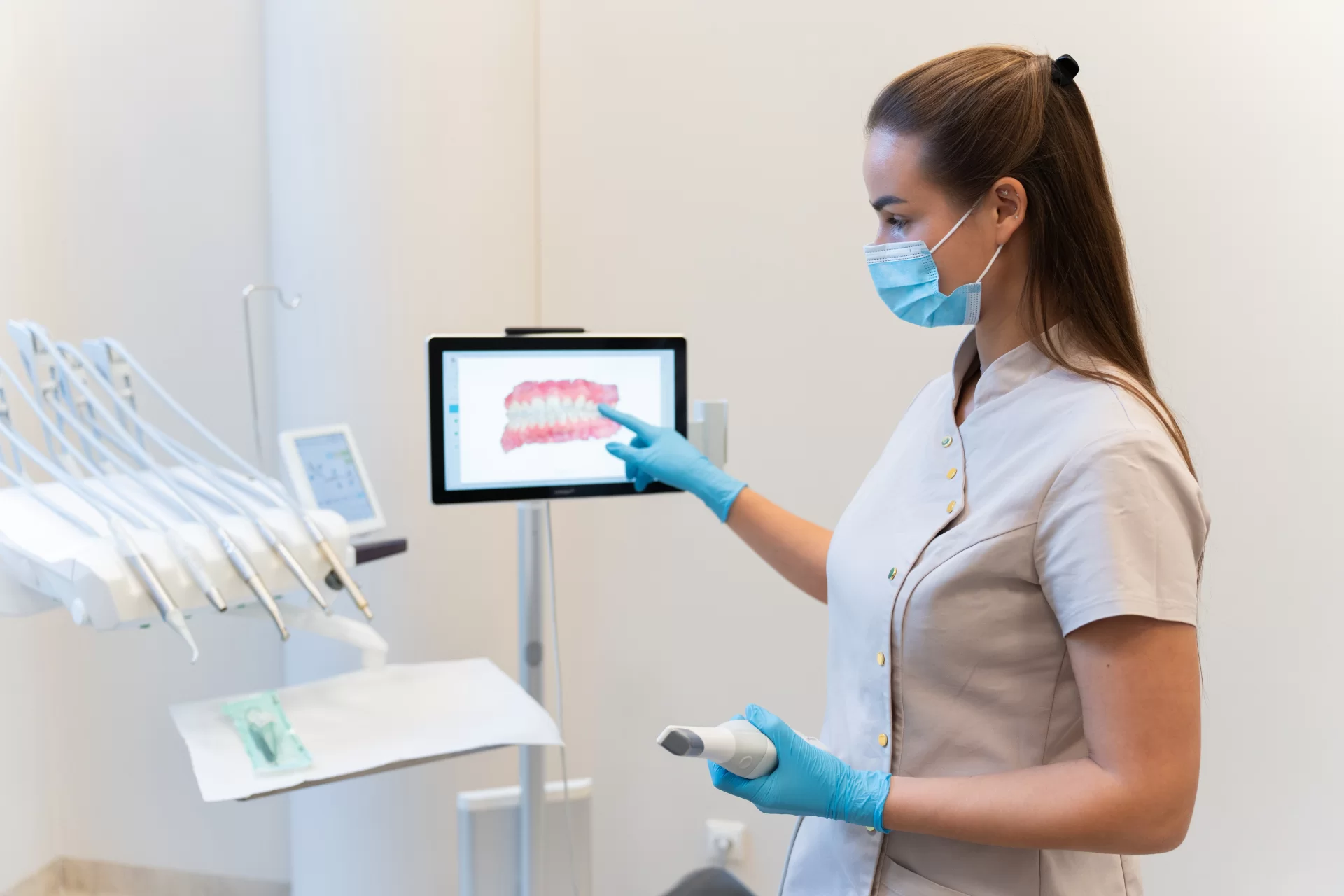 Odontologė su pirštine rodo paciento dantų vaizdą ekrane konsultacijos metu